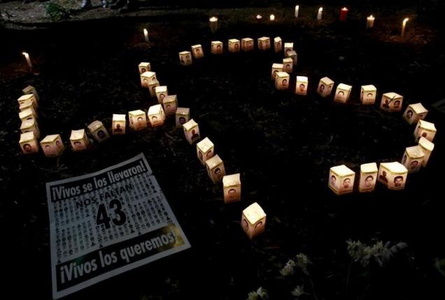 Candles burn beside pictures of some of the 43 missing students, on the six-month anniversary of their disappearance, during a vigil outside the office of Mexico's Attorney General in Mexico City, March 26, 2015. REUTERS/Henry Romero